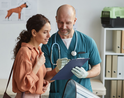 Un médico veterinario explicando algo en su bitacora a mujer